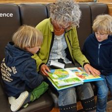 Isoäiti lukee kirjaa kahdelle lapsenlapselle