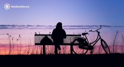 Henkilö istuu puistonpenkillä yksin ja katselee auringonlaskua